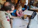 At the February 18 TDOTA event for Girl Scouts in Bellevue, Nebraska, Jim Taylor, AJ0R, helps Brownie Tegan talk with other girls in London via EchoLink. [Photo courtesy of Dudley Allen, KD0NMD]